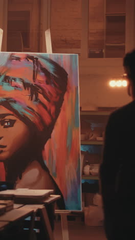 artist viewing a colorful portrait painting in a studio