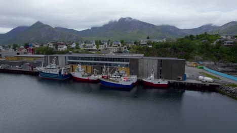 aerial sideways close up shot of the fish industry on husoy island, senja, northern norway