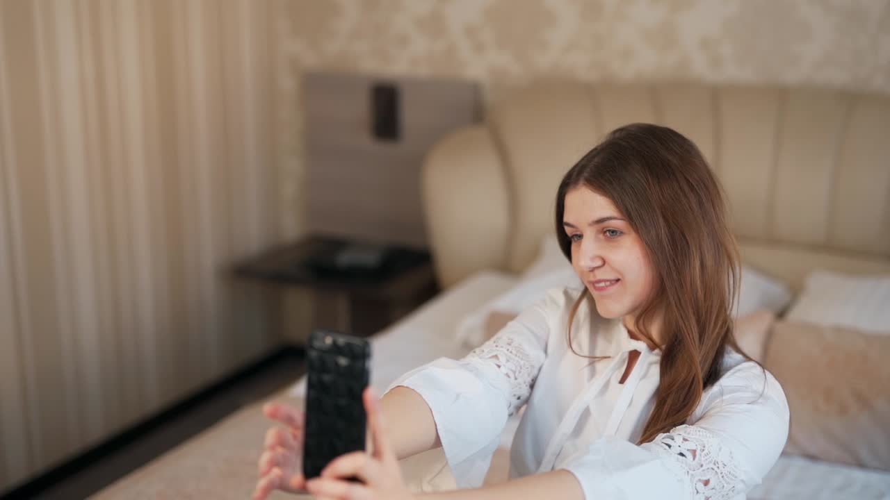 elegante mujer joven de negocios se toma un selfie en un teléfono inteligente en la cama en una habitación de hotel