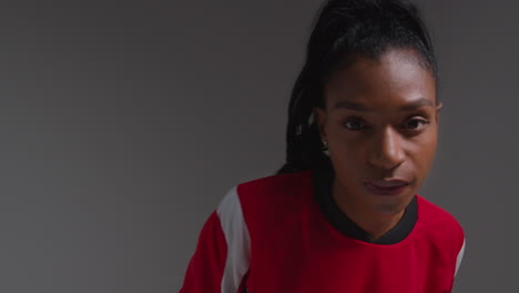 Studio-Portrait-Of-Serious-Female-Football-Or-Soccer-Player-Wearing-Team-Shirt-Holding-Ball-Under-Her-Arm-Shot-Against-Grey-Background-3