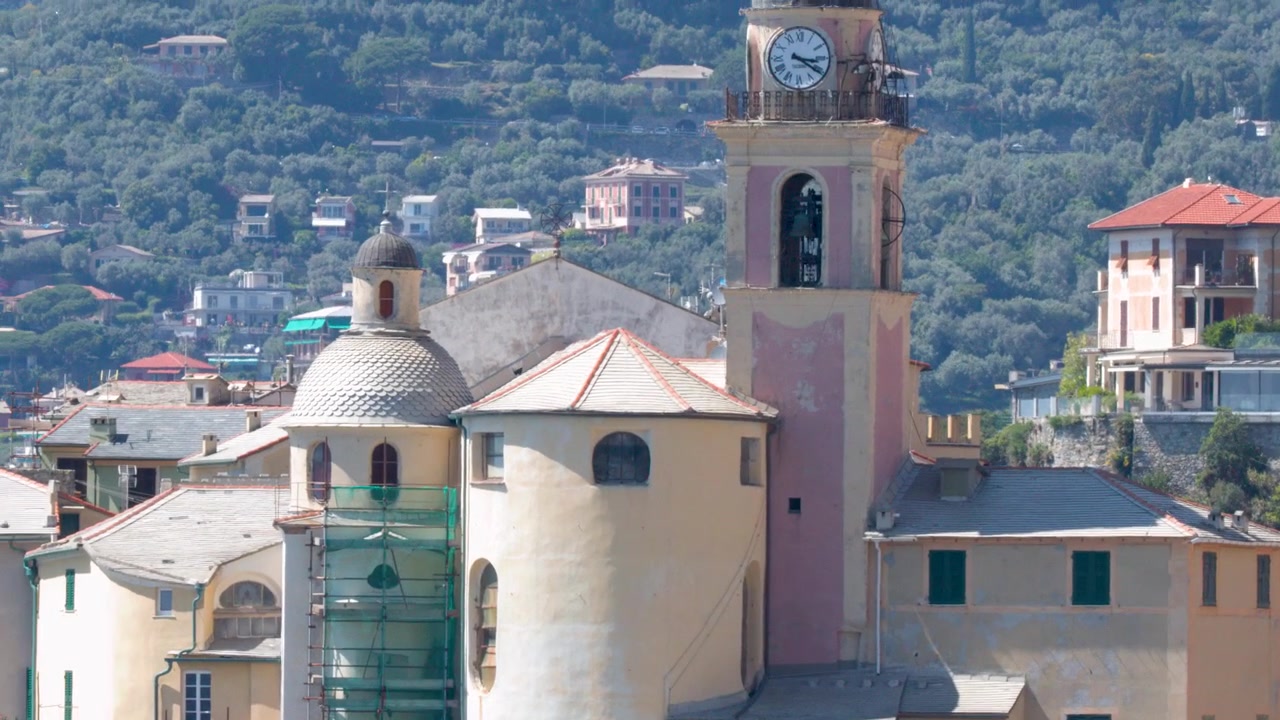 Un lento zoom all'indietro rivela un campanile di chiesa storico contro una collina rigogliosa.