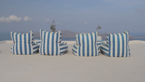 stripped blue and white chairs on a terrace overlooking the majestic seascape of a greek island