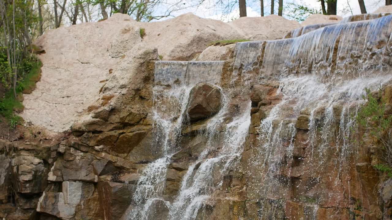 hermosa cascada desde un acantilado en el bosque. 4k video de agua que fluye, arroyo que fluye entre las piedras. arroyo en el bosque