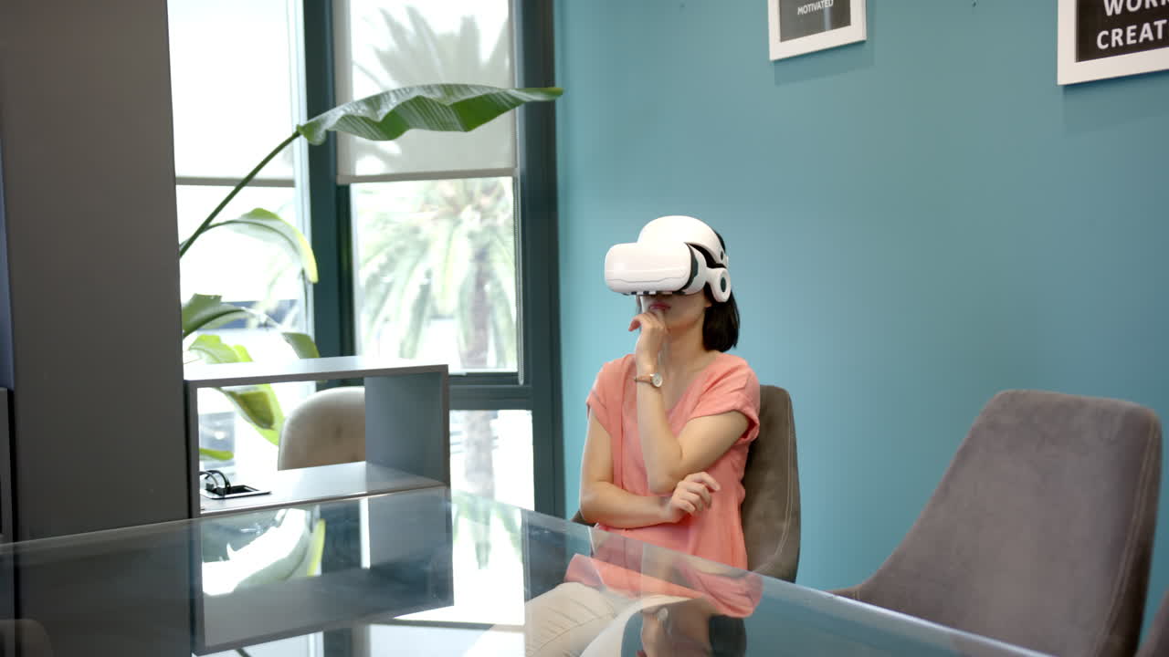 Using VR headset, woman sitting at desk in modern office environment