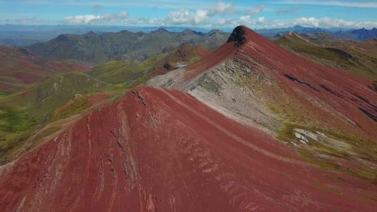 Aerial, tracking, drone shot of red mountains, near the Palcoyo rainbow mountain, in Valle Rojo Valley, Andes, Peru, South America