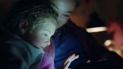 madre e hijo usando una computadora tablet madre enseñando a una niña pequeña jugando juegos en tecnología de pantalla táctil divirtiéndose antes de acostarse