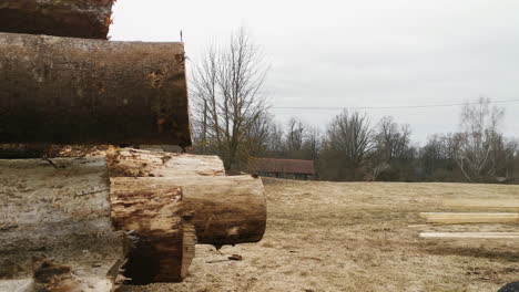 Worker-drives-tractor-pulling-cargo-with-sawed-wooden-planks