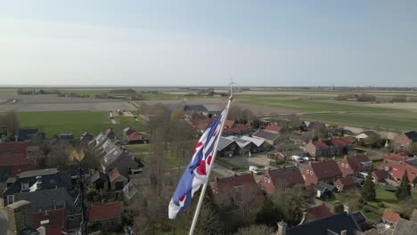 Frisian-flag-waving-on-church-tower-in-rural-town-of-Pingjum,-Holland