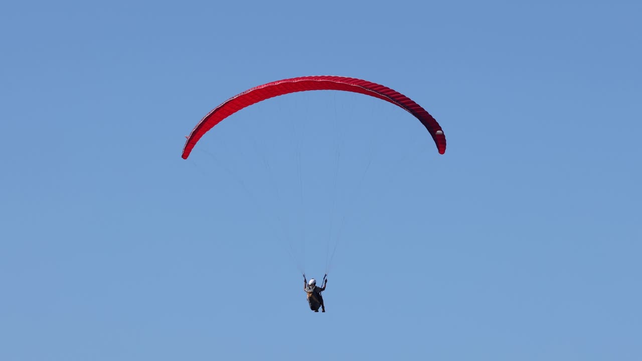 Paraglider soaring in clear blue sky