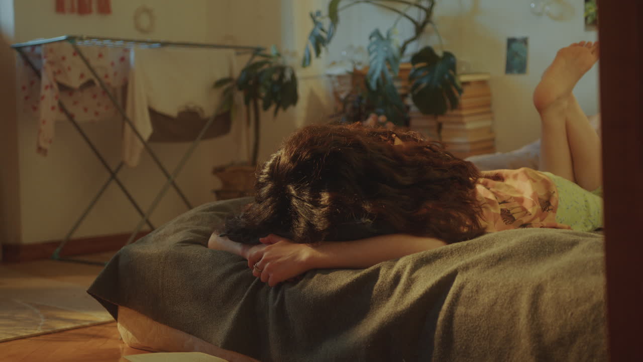 편안한 방에서 침대에 책을 읽는 소녀, 으로 놓고 얼굴을 아래로 누워