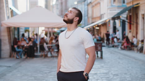rear view of young man tourist walking through the street outdoors looking searching for a way
