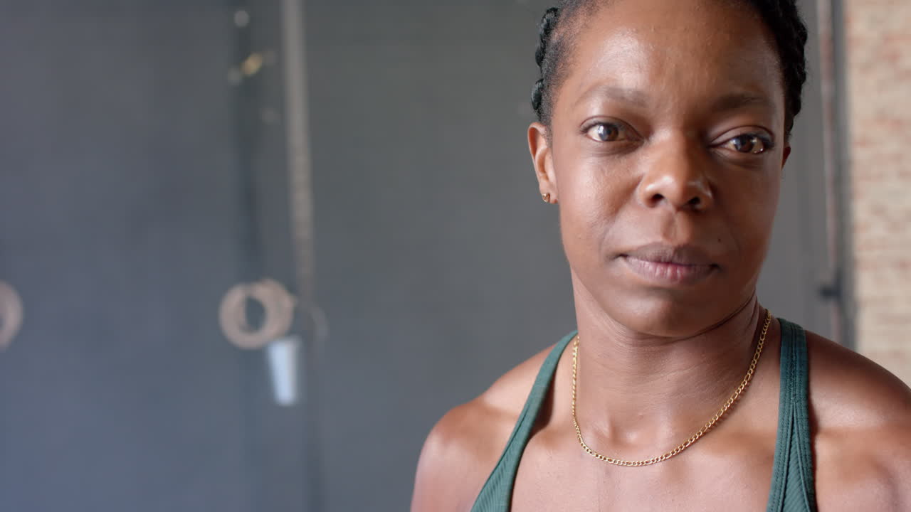Close-up of woman in gym wearing sportswear, looking confidently at camera, copy space
