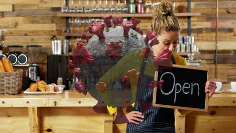 animation of macro covid-19 cell floating over happy caucasian female chef holding open sign