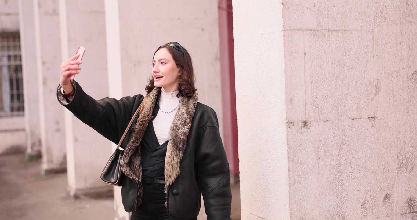 Donna blogger felice si scatta selfie con lo smartphone per strada