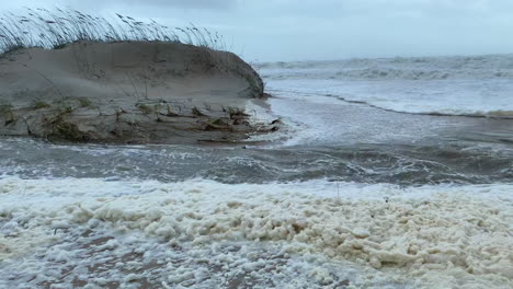 hurricane surge waters flooding beach and sand dunes while making landfall