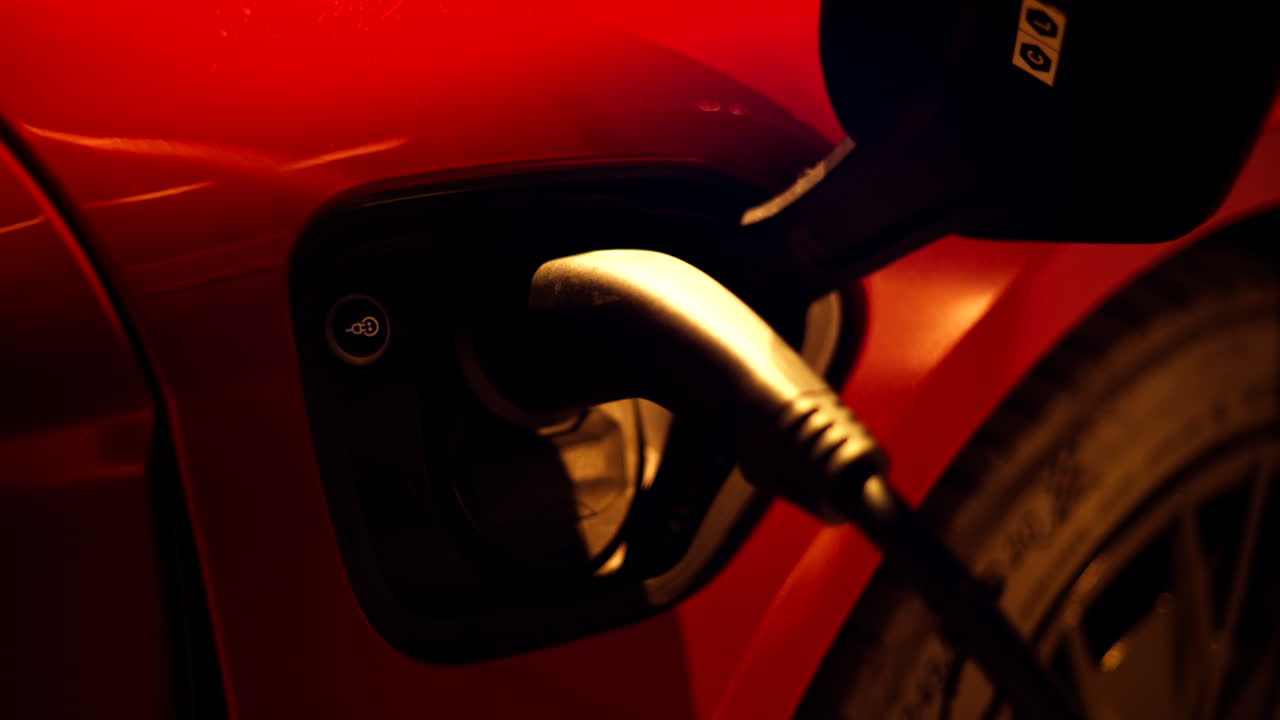 Red, electric car charging on the street at night