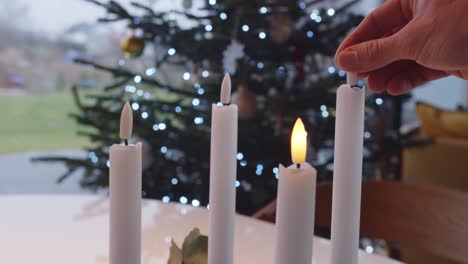 turning on electric candles one by one christmas tree in background