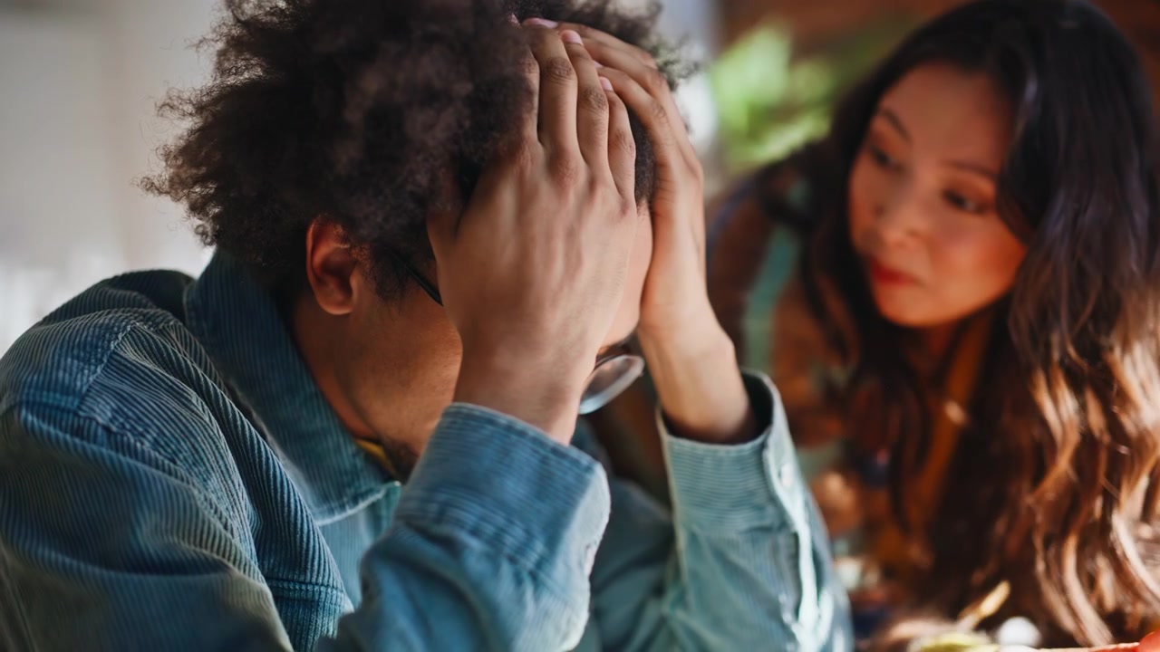 Bad news phone call. Stressed man holding head, worried coworker office loft.