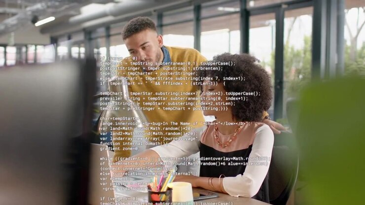 Woman at laptop pointing, man leaning and causing code overlay obscuring screen while fixing code