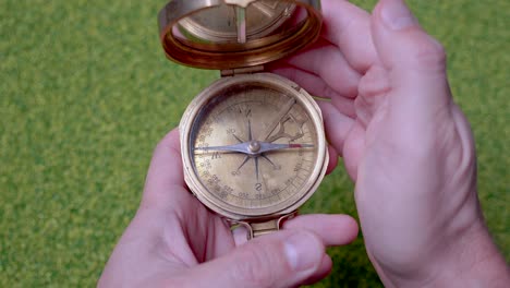 close up shot of man checking golden compass for direction outdoors in wilderness