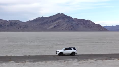 drone shot of white suv vehicle on road in bonneville salt flats, utah usa