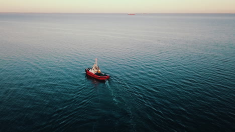 Drone-flying-above-fishing-boat-sailing-on-the-sea-at-the-sunset