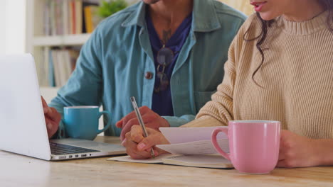 Primer-Plano-De-Una-Pareja-En-Casa-Con-Una-Computadora-Portátil-Revisando-Las-Finanzas-Para-Iniciar-Juntos-Un-Negocio-Independiente