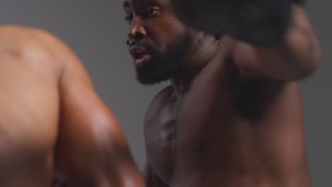 close up studio shot of two male boxers wearing gloves fighting in boxing match against grey background 3