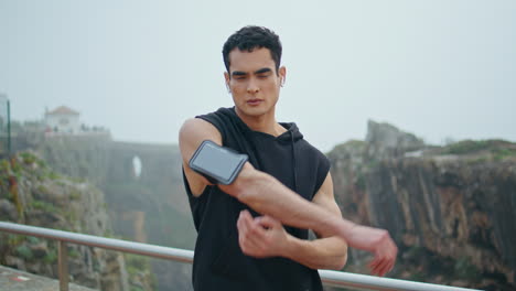 fit guy stretching hands outdoors. handsome sportsman training in urban park