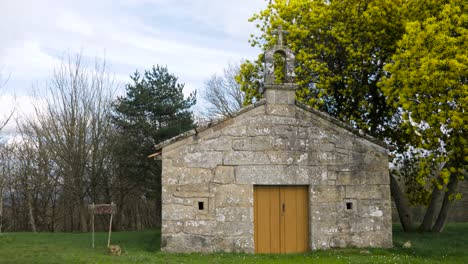 Kapelle-Von-San-Vitoiro,-Mittlere-Ansicht-Von-Alten-Holztüren-Um-Geschnitzten-Stein-Unter-Gelbem-Baum