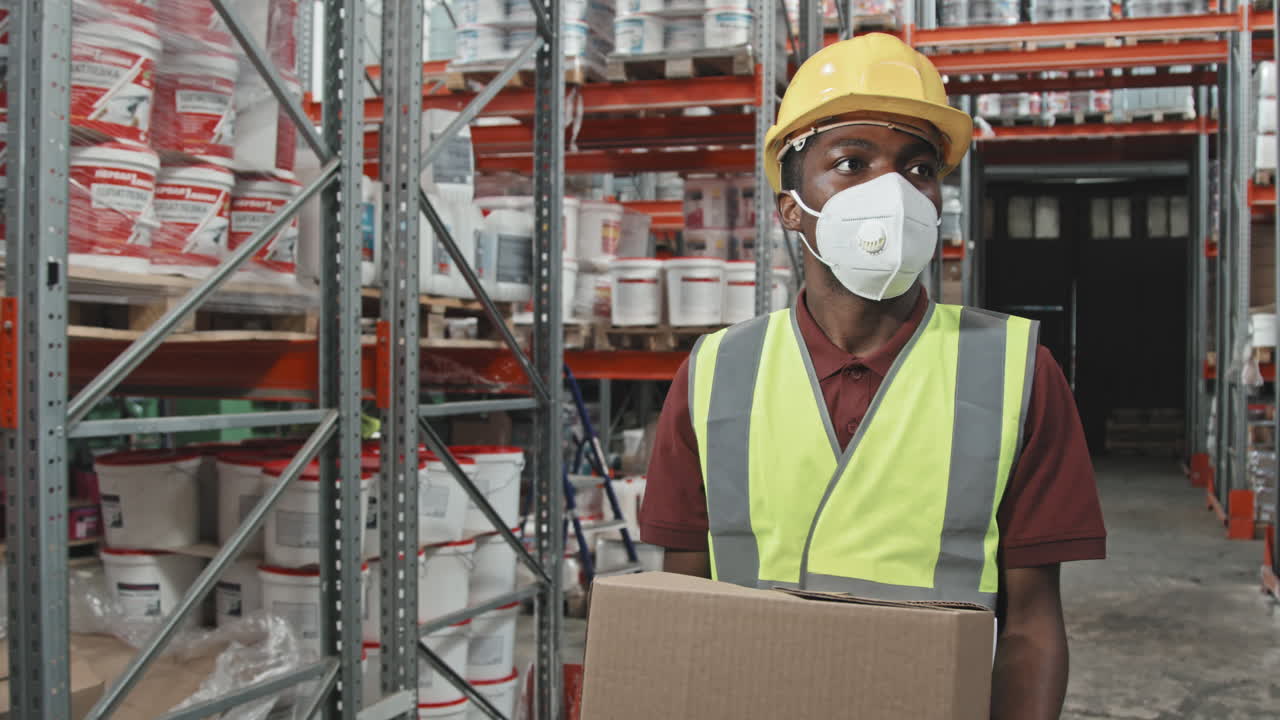 Black Male Worker Carrying Boxes in Warehouse