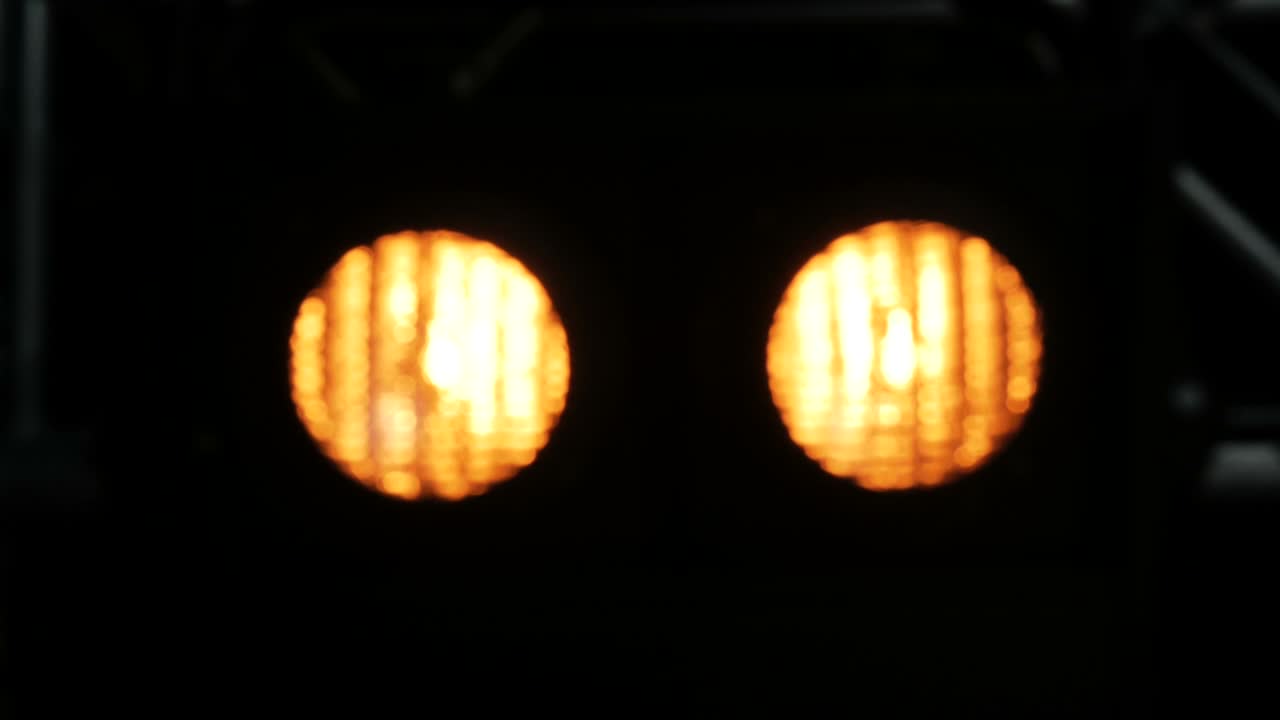 노란 빛의 흐릿한 배경, 검은 무대 위의 불빛.