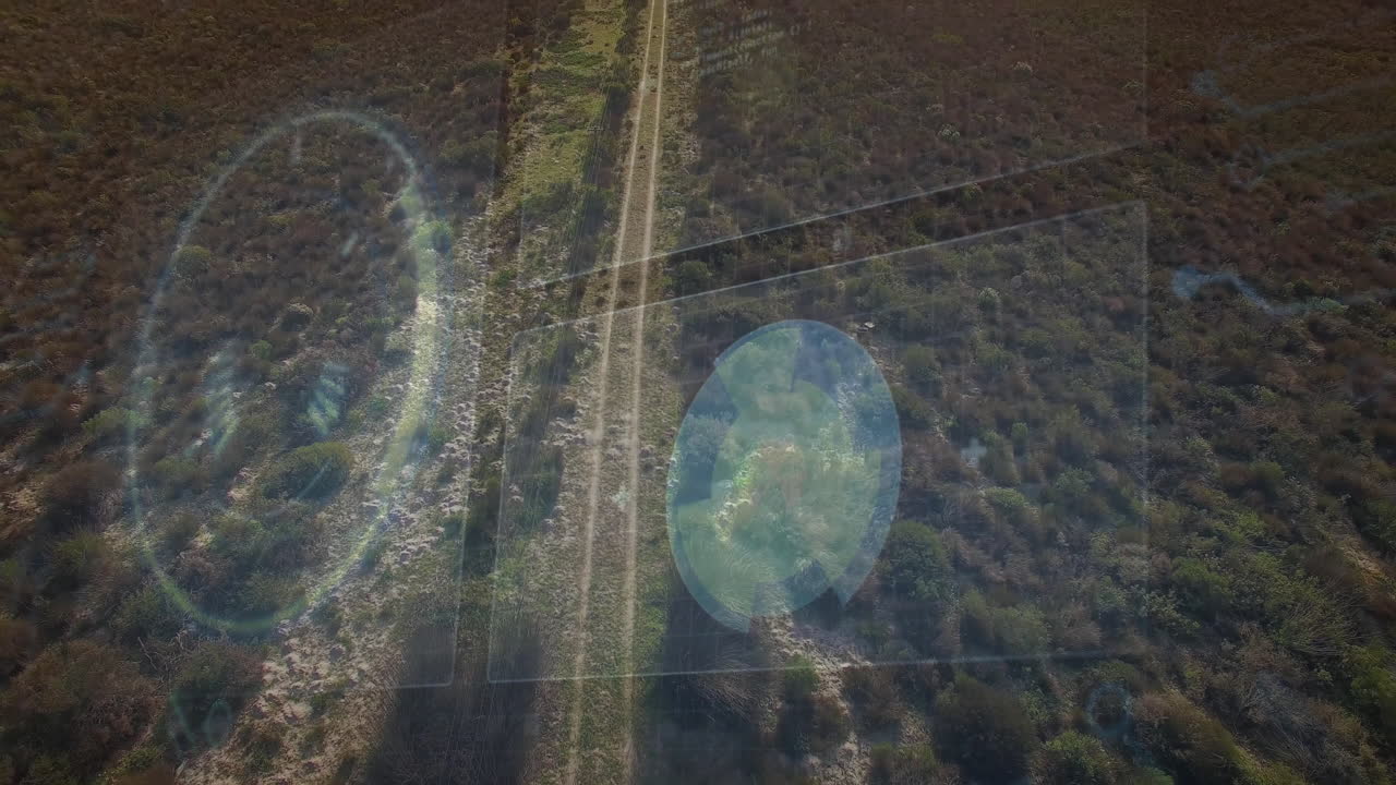 Drone surveying scrubland from above, showing double-track dirt road with UI grid overlay lines