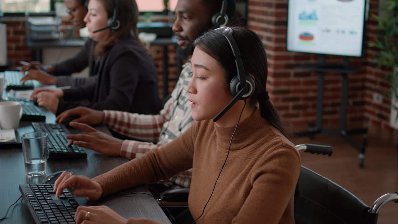 Female worker in wheelchair talking on phone helpline at call center