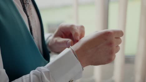 El-Novio-Ajustando-Su-Puño,-Destacando-Una-Elegante-Pulsera-Y-Un-Elegante-Traje-De-Boda.