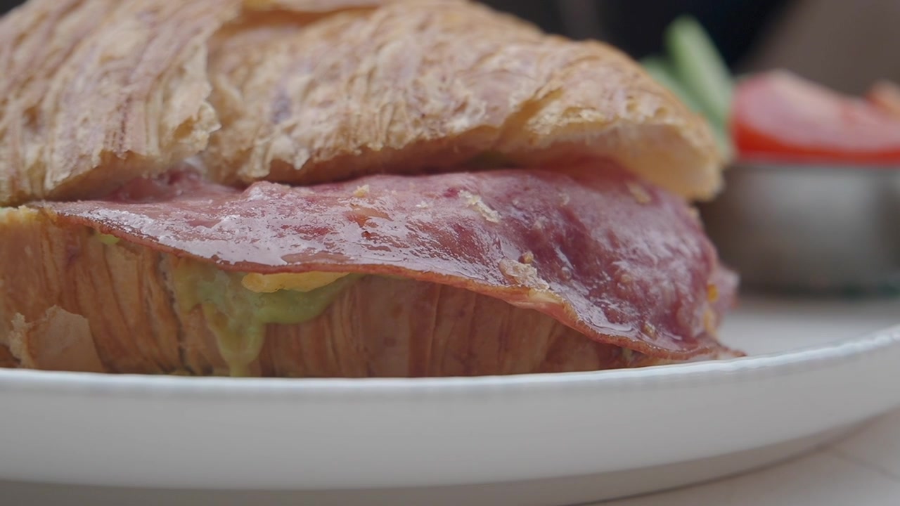 Primo piano di un delizioso croissant salato con pancetta e avocado