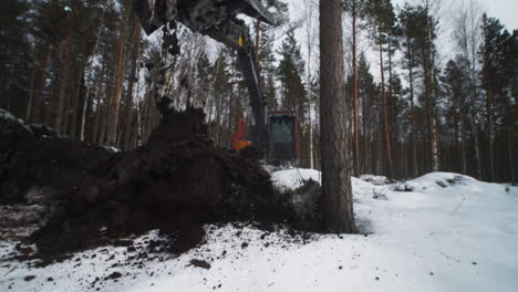 large excavator digging and dropping dirt pile in forest