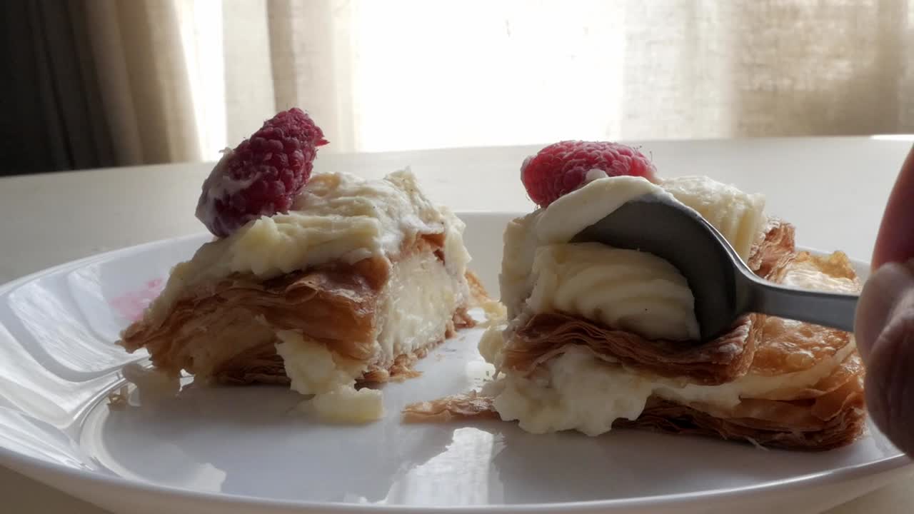 Flaky layers of millefeuille dessert with raspberries and cream filling, close-up shot