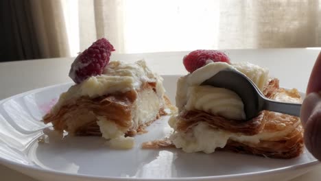 flaky layers of millefeuille dessert with raspberries and cream filling, close-up shot