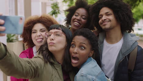 portrait of happy group of multi ethnic friends posing taking selfie photo using smartphone enjoying fun making faces students celebrating vacation together