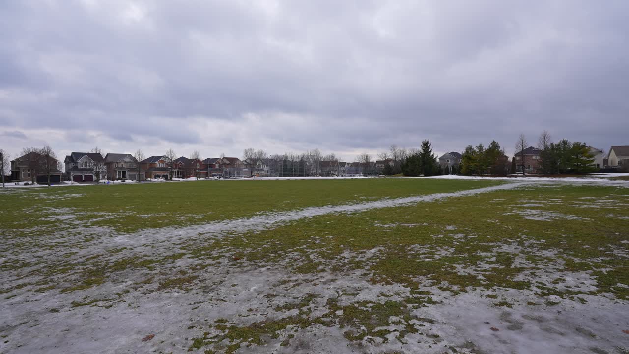 Campo coperto da chiazze di ghiaccio e neve al Kinross Park, Oshawa, Ontario, Canada.