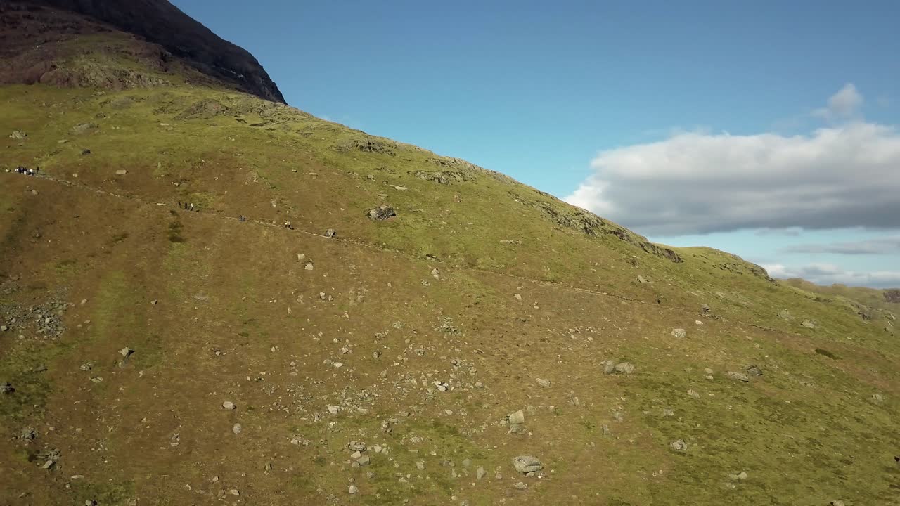여름날 일부 구름과 함께 거대한 산을 내려가는 일부 사람들의 공중 하향식 샷