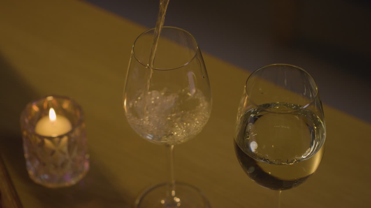primer plano de verter vino en copas para una velada romántica en casa en el salón con velas
