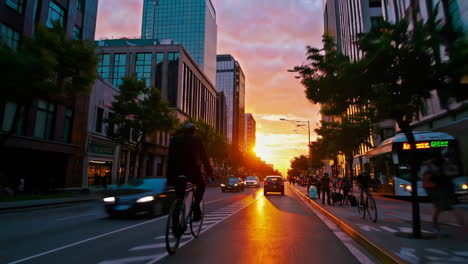 cyclist riding through a vibrant city street at sunset