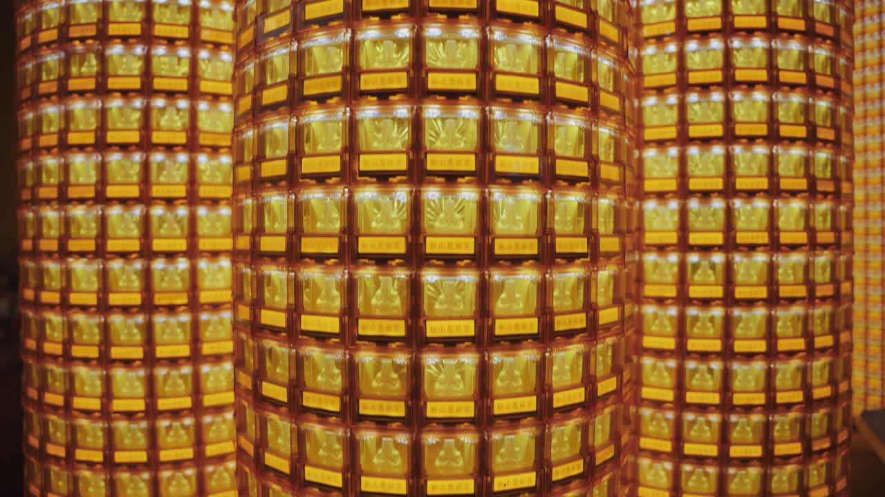 Symmetrical close-up of golden Buddha statues glowing in individual illuminated niches at Ciyou Temple in Taiwan, symbolizing devotion, peace, and spiritual reverence in a sacred Buddhist space