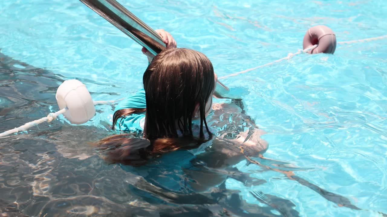 Child holding onto a rail in a swimming pool