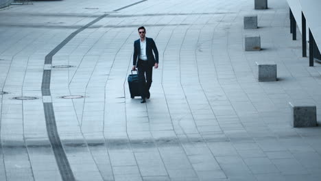 Close-up-view-of-handsome-businessman-walking-with-luggage-on-sidewalk