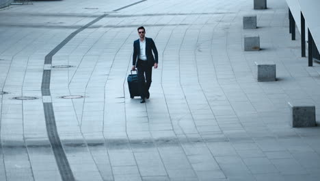 close up view of handsome businessman walking with luggage on sidewalk