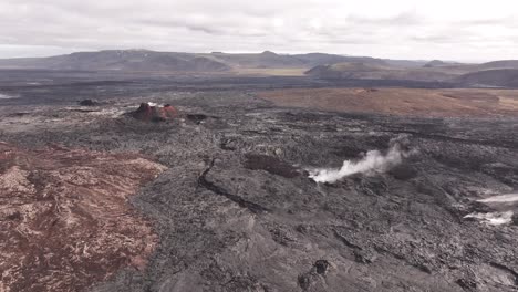 volcanic landscape with dark lava crust and rising smoke in iceland