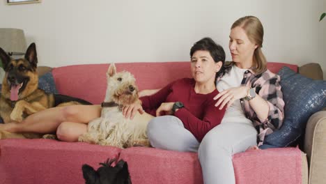 Caucasian-lesbian-couple-talking-to-each-other-sitting-on-the-couch-with-their-dog-at-home